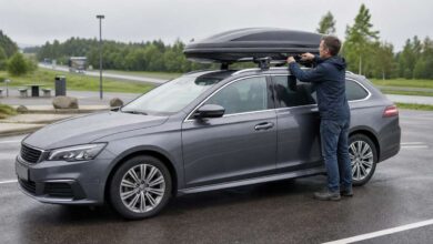 Fahrer prüft die Befestigung einer Dachbox auf einem Kombi