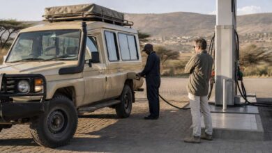 Reisender und Tankwart an einer Tankstelle in Kenia vor einer Safari mit dem Mietwagen