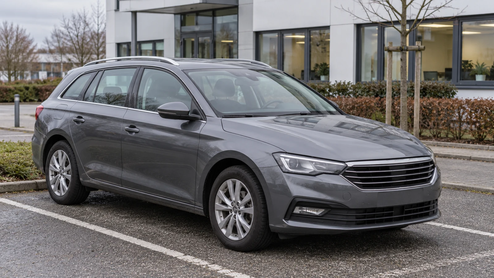 Grauer Firmenwagen auf einem Parkplatz vor einem Bürogebäude